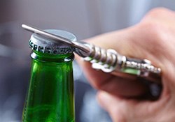 Person removing bottle cap with a bottled beverage