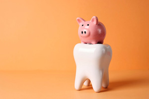 Pink piggy bank on large model tooth with orange background