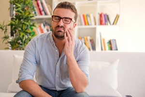 man with a toothache holding his cheek
