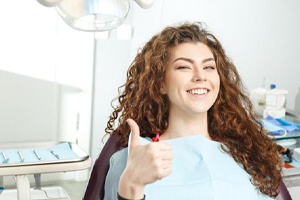 woman giving a thumbs-up after undergoing root canal therapy from her dentist in Fort Worth