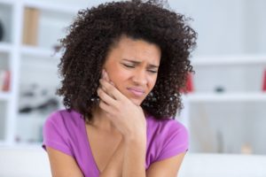 woman holding her face due to tooth pain 