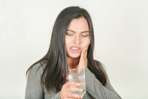 Woman experiencing tooth sensitivity. 