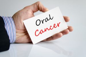 Dentist in Hulen holding oral cancer card