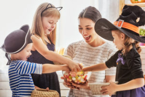 Mom with three kids in Halloween costumes eating candy