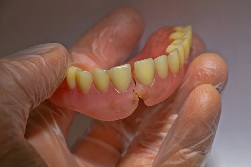 A hand holding a broken denture